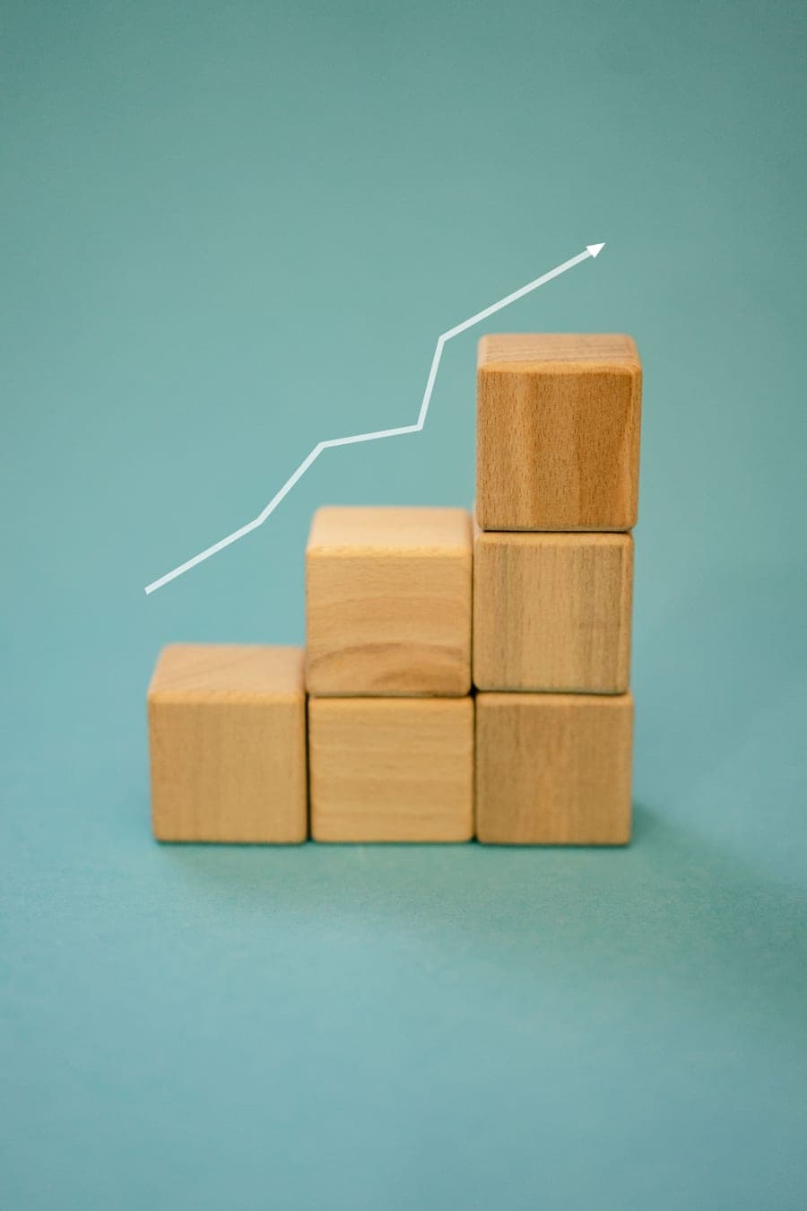 Wooden blocks stacked like rising steps beneath an upward arrow
