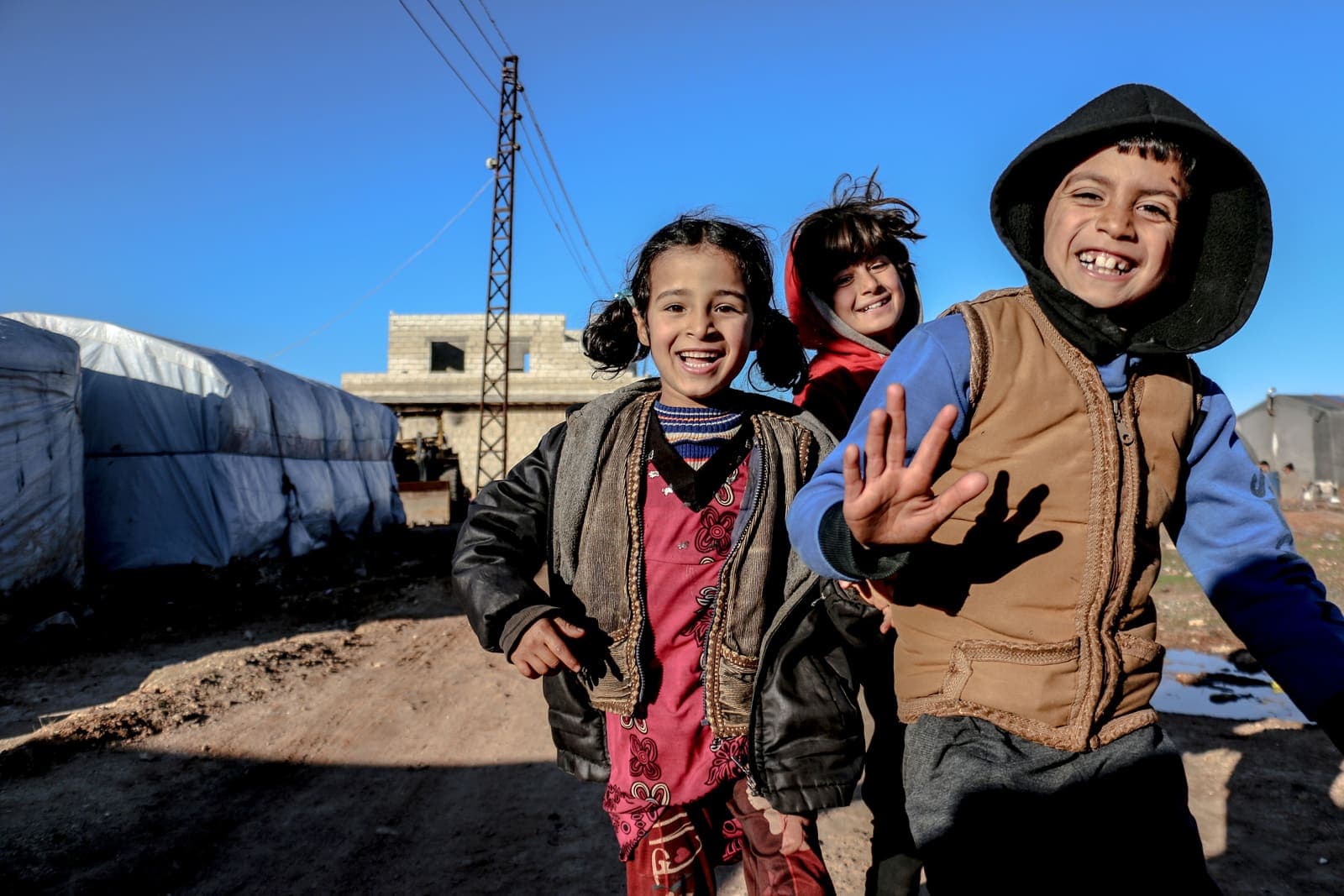 Smiling children waving at a camp