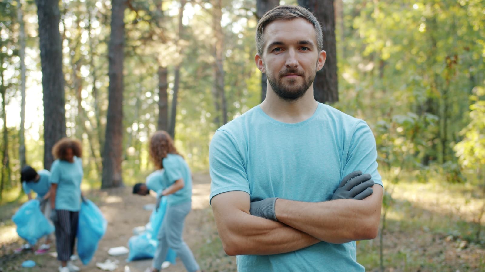 A volunteer standing with arms crossed during a forest clean-up
