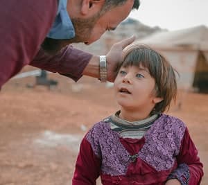 A man gently touching a young girl's head