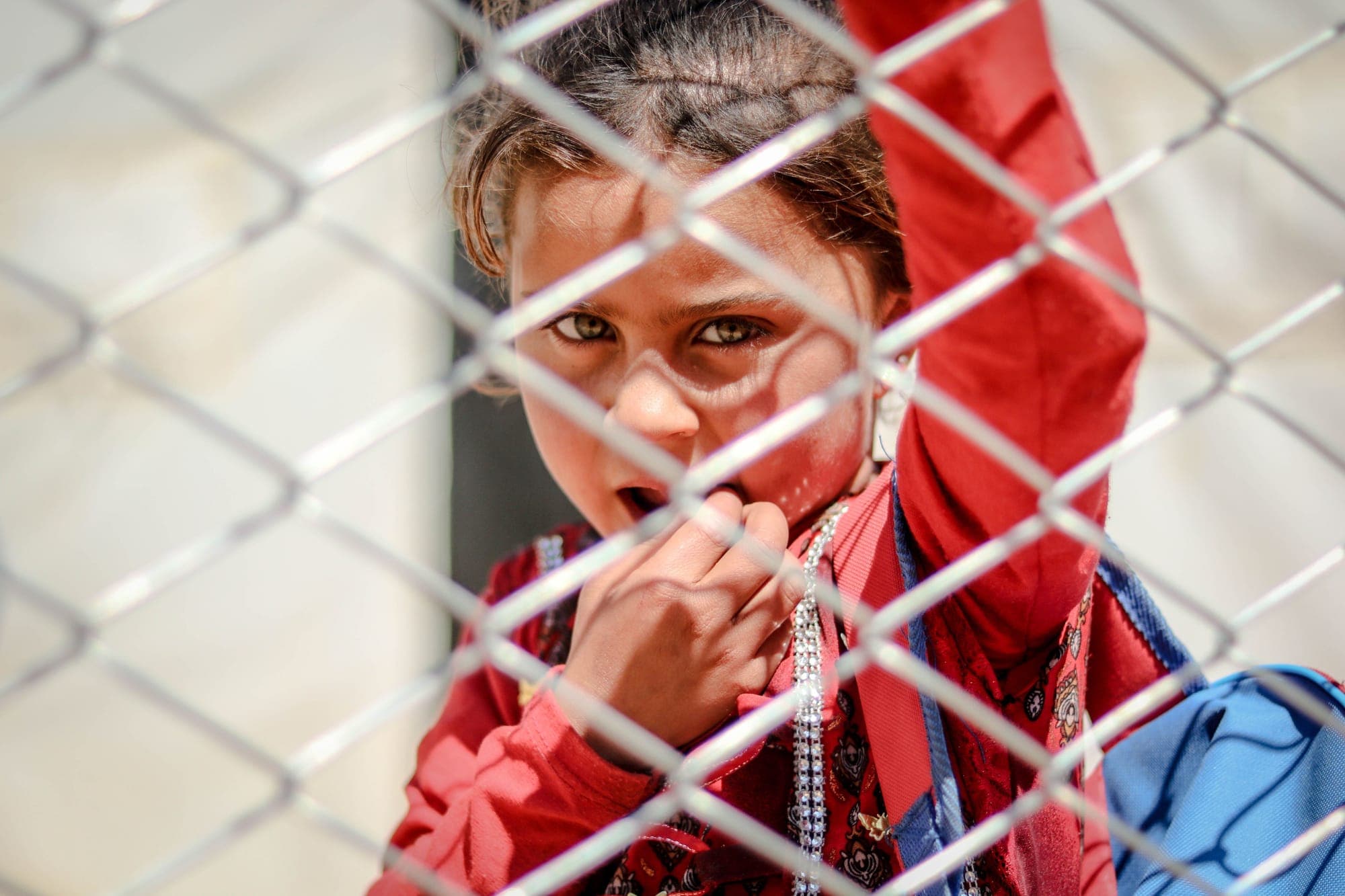 A young girl looking through a fence