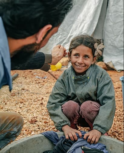 A smiling young girl washing clothes outdoors
