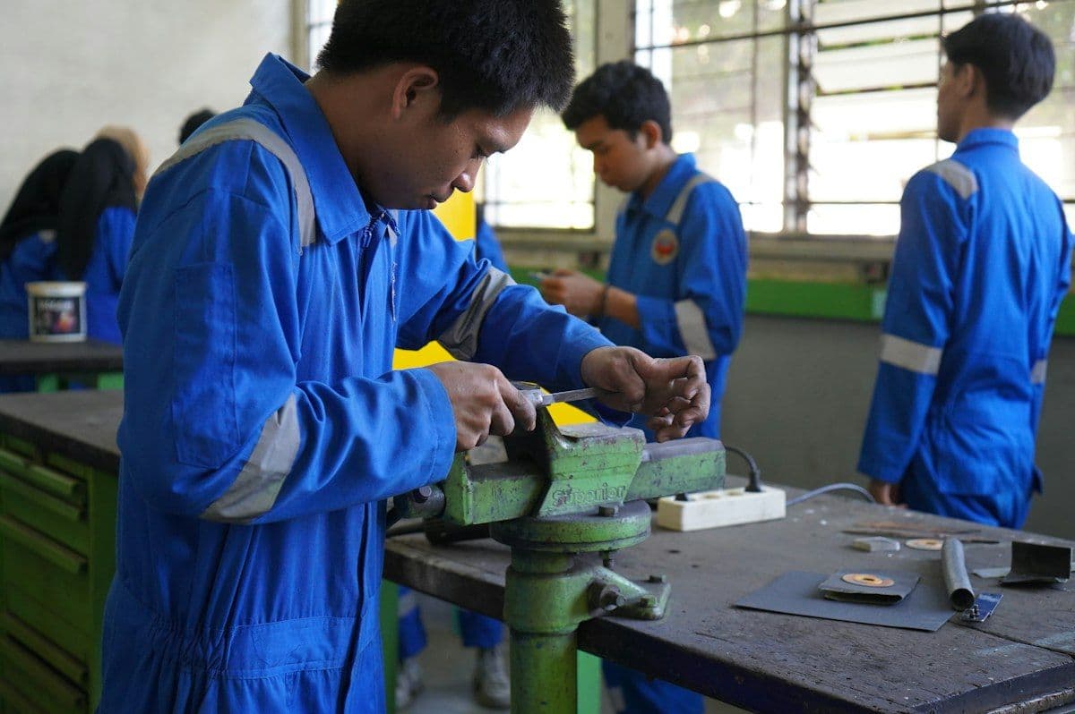 A group of people working together on a piece of metal in a workshop