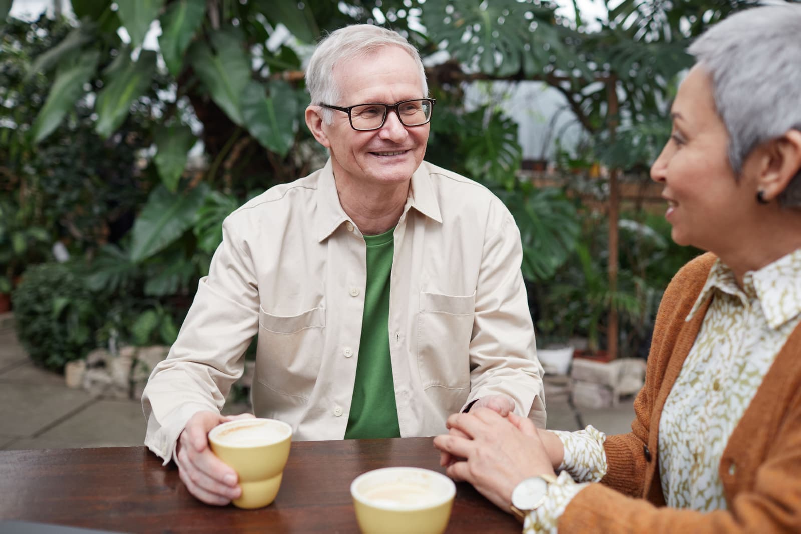 Two older adults talking warmly over coffee