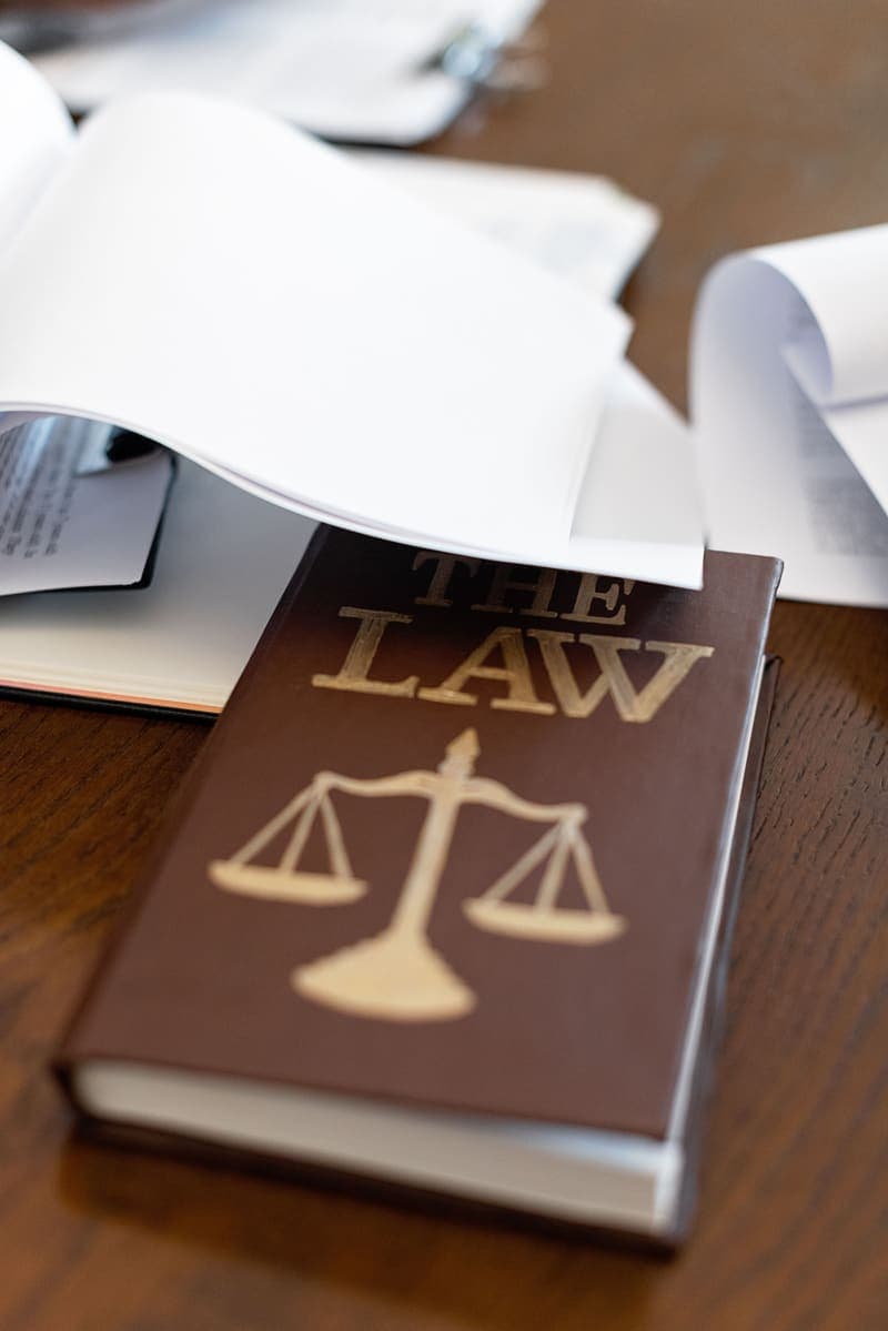 A law book with scales of justice resting under open documents