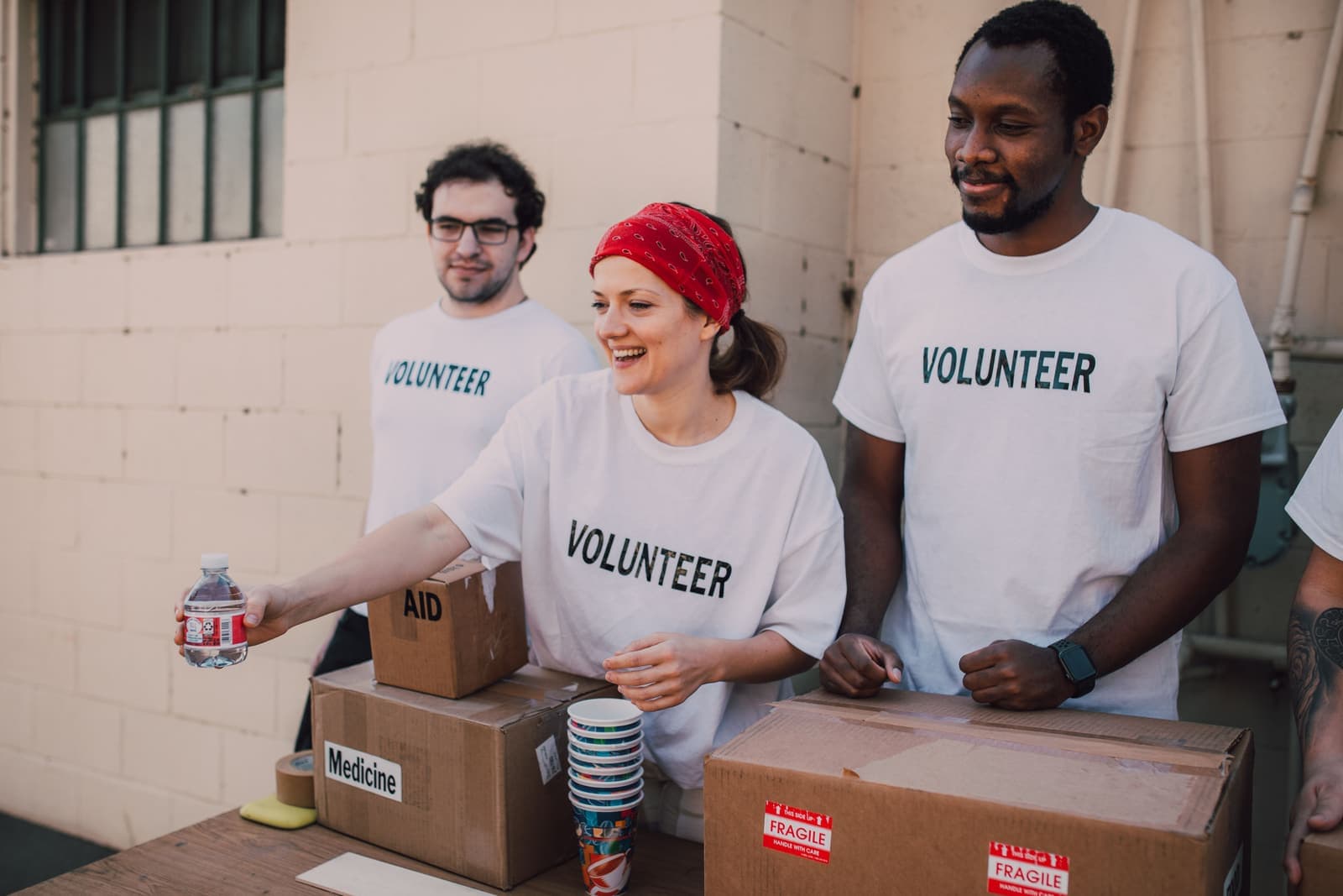 Smiling volunteers handing out water beside aid boxes